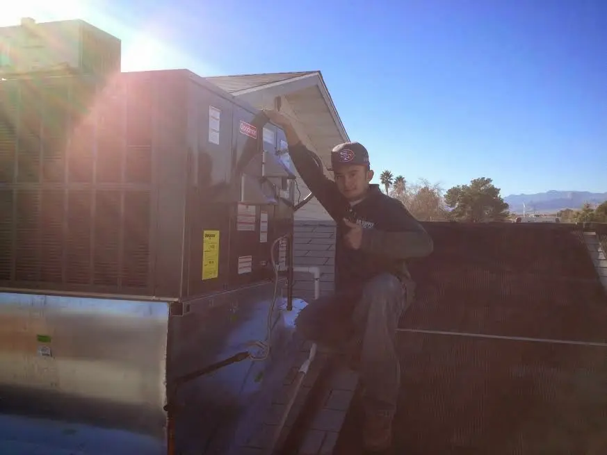HVAC technician performing Heat Pump Repair on a rooftop unit in Friendswood